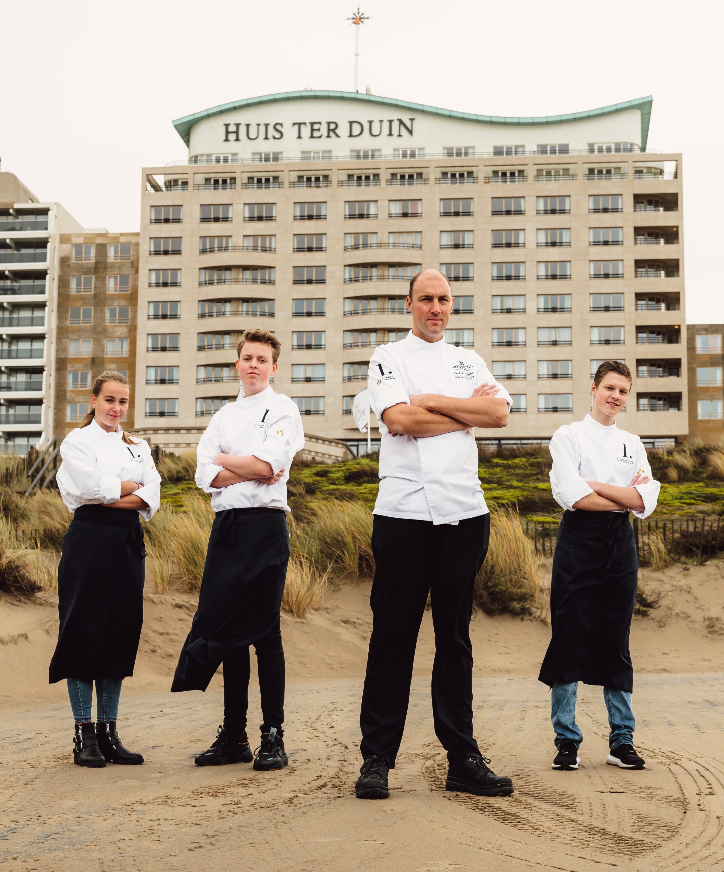 Vier chef koks in koksbuis op het strand staand voor Huis ter Duin