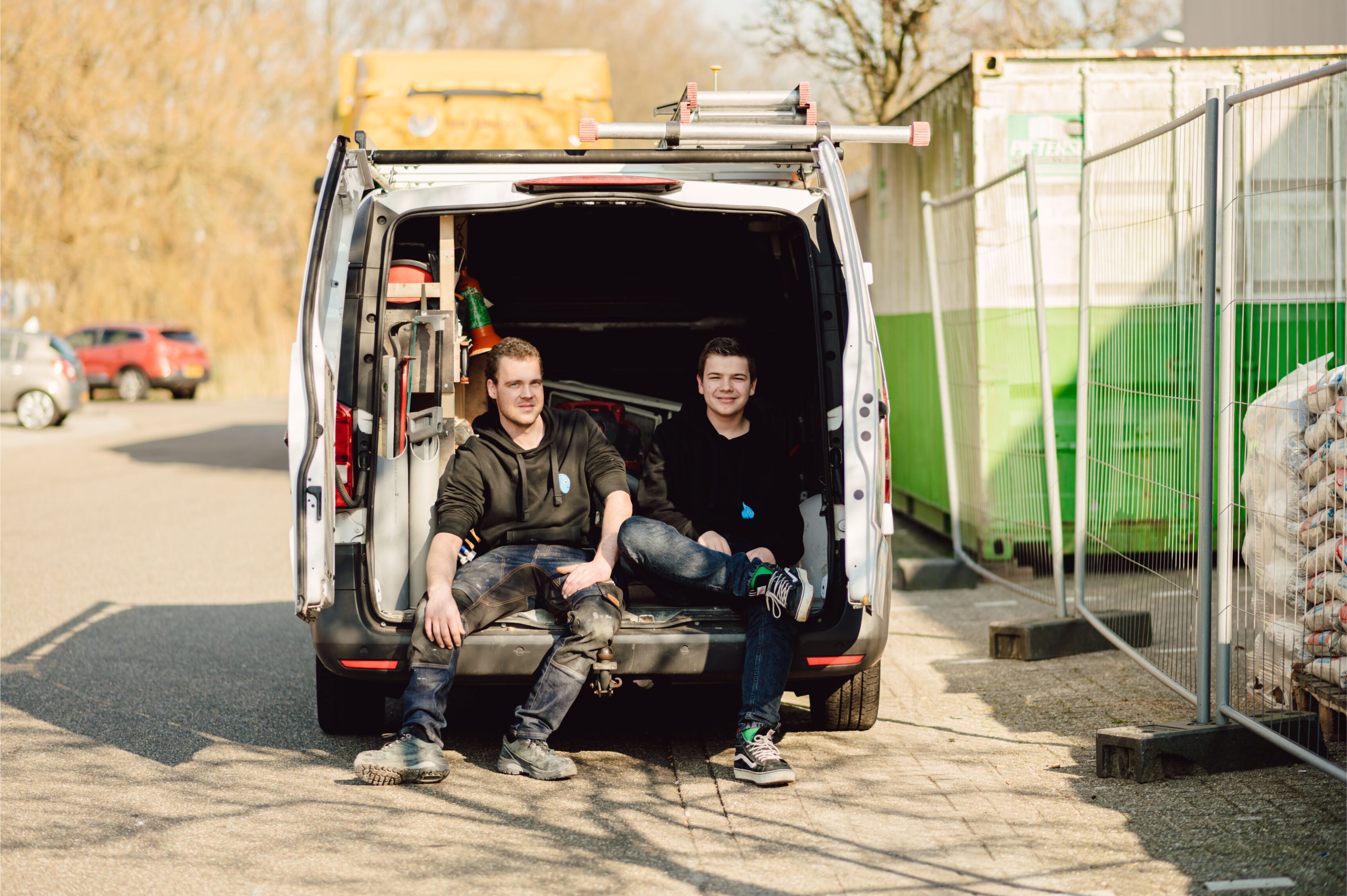 Twee medewerkers die in achterbak van werkbus zitten