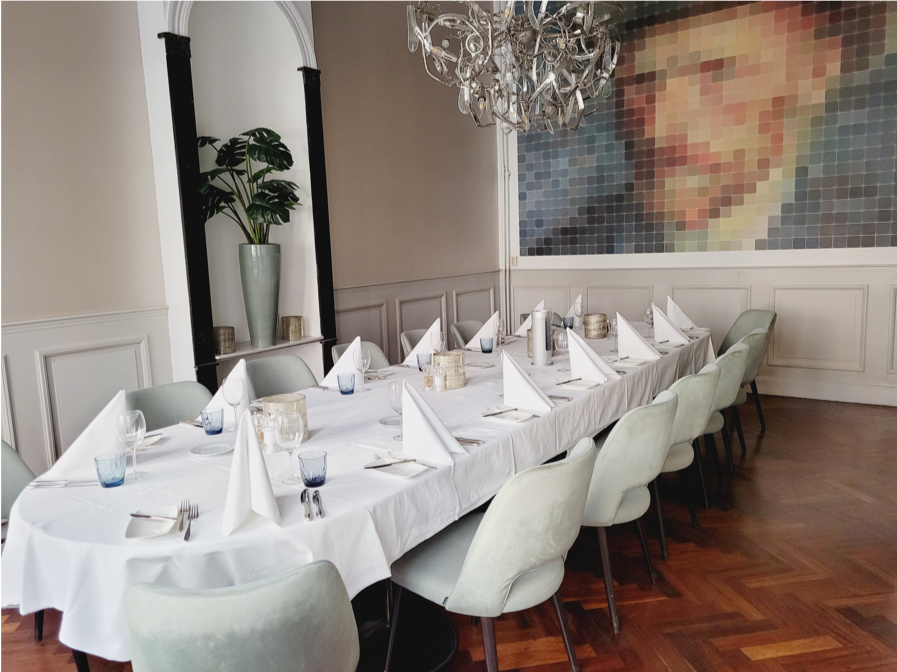 gedekte tafel in eetzaal in restaurant Het Prentenkabinet met schilderij van zelfportret van Van Gogh op achtergrond
