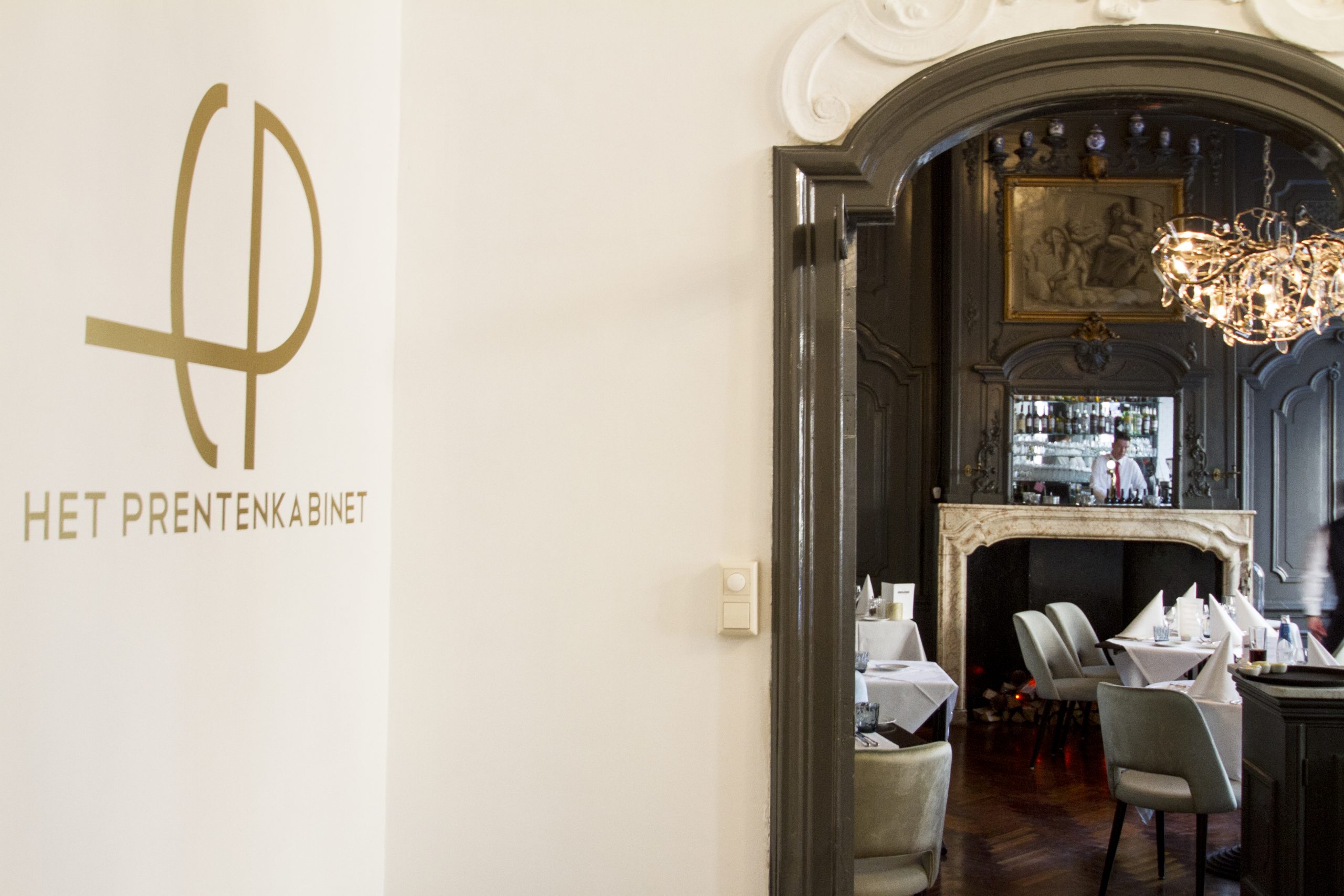 Doorkijkje in restaurant Het Prentenkabinet met logo aan de wand